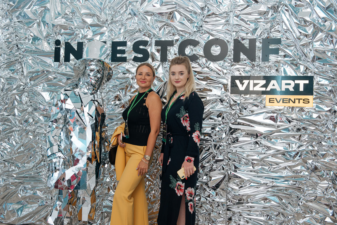 Девушки фотографируются с человеком в блестящей одежде на InvestConf InvestConf блестящий человек