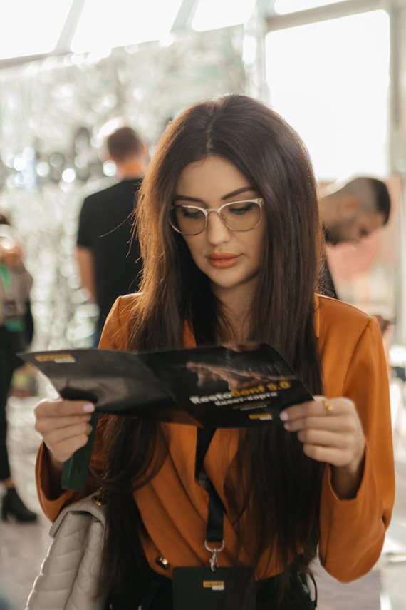 Участница RestoConf Девушка читает рекламный буклет