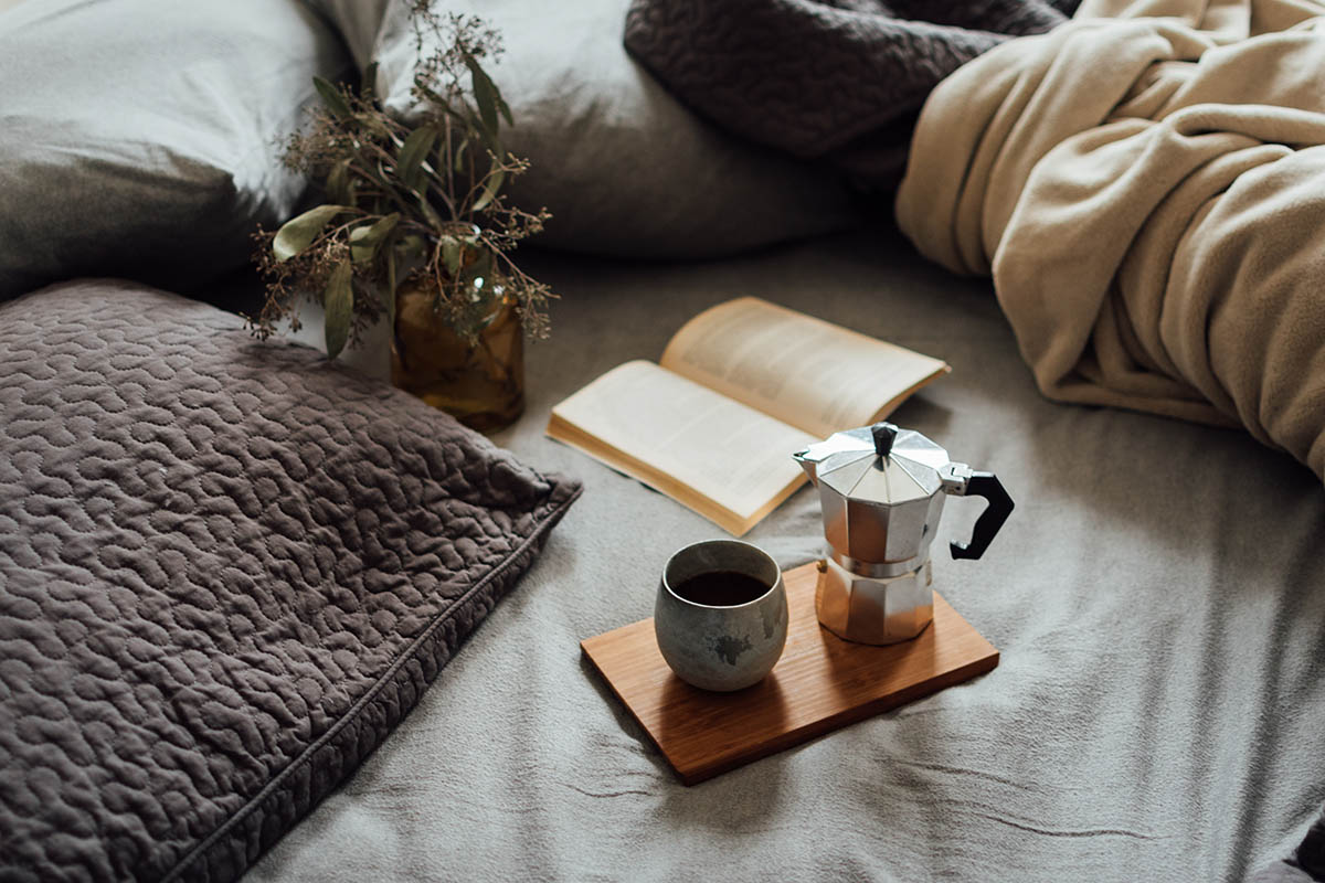 Чашка кофе на кровати с книгой